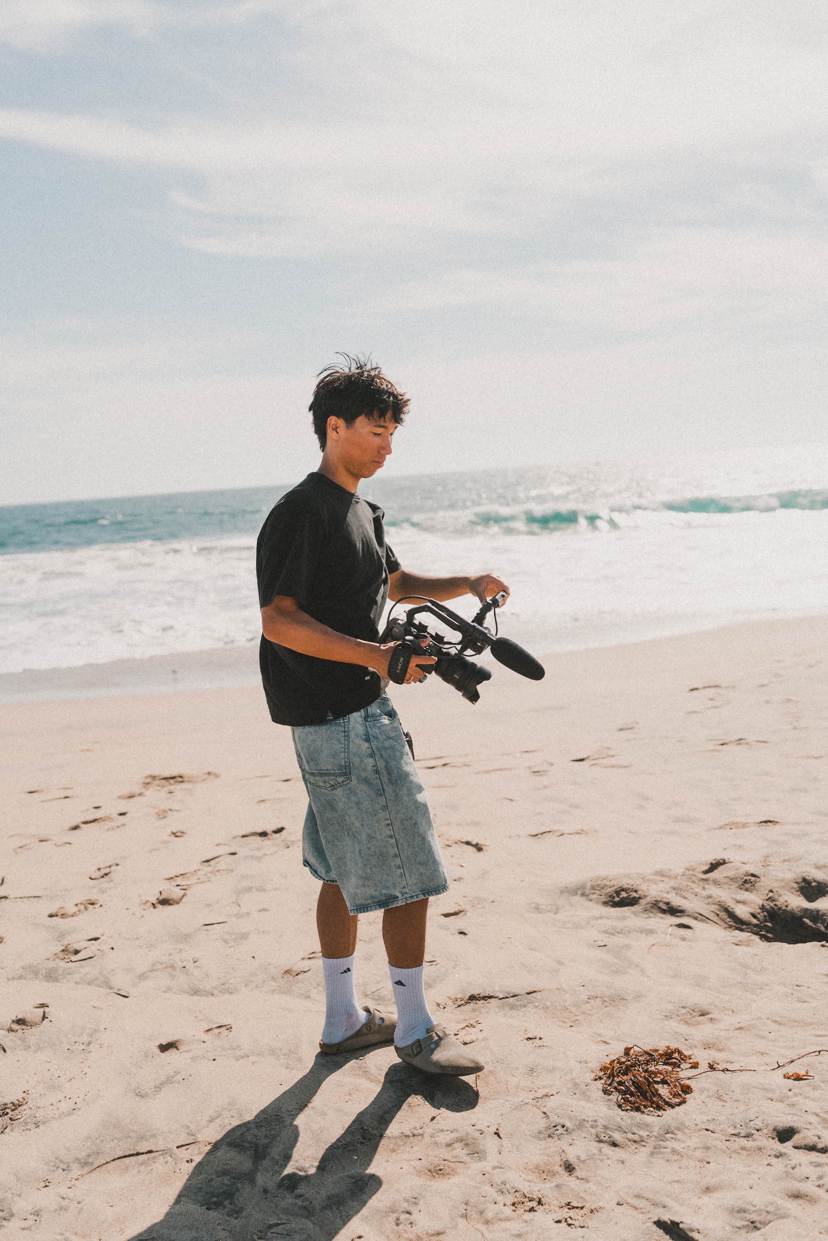 Jared Ho holding a camera on a beach